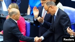 Friederich Merz (dreapta) este felicitat de fostul cancelar Olaf Scholz după ce a obținut votul Parlamentului german.