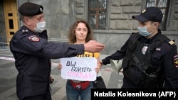 Police officers detain a journalist who holds a placard reading "You Are Afraid Of The Truth" during a single-picket protest against the "foreign agent" law in Moscow in August 2021.