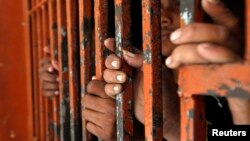 Indian fishermen from a previous round of detentions stand behind bars in Karachi, Pakistan.