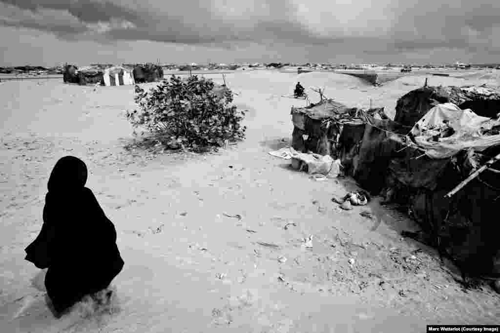 On the outskirts of the port town of Gwadar, a Baloch woman returns to her home, built primarily from branches and cloth rags.