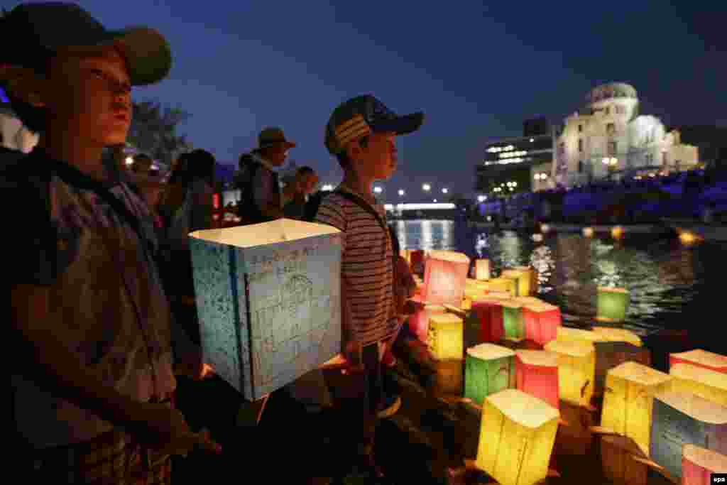 Хлопчики готуються спустити на воду паперові ліхтарики, щоб заспокоїти душі жертв атомного бомбардування Хіросіми, Меморіальний парк миру, 6 серпня 2015 року