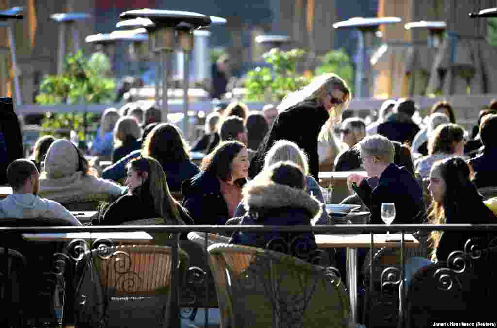 Наслаждающиеся весенним солнцем стокгольмцы на открытой площадке столичного ресторана. 26 марта 2020 года.