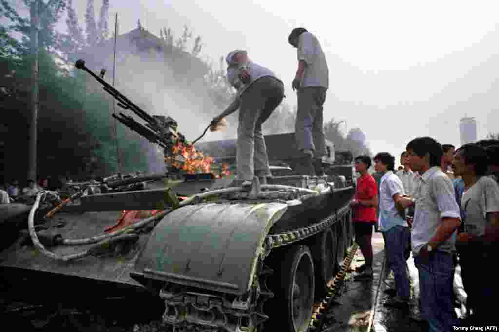 Chinese residents check a burning armoured personnel carrier which was put in on fire by rioters fighting back when the army opened fire on the civilians on June 4, 1989 near Tiananmen Square in Beijing.
