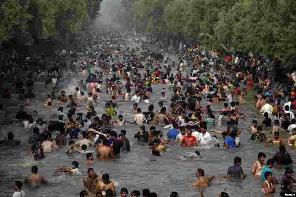 People cool down in a canal in the eastern Pakistani city of Lahore as temperatures reach 43 degrees Celsius on June 9.