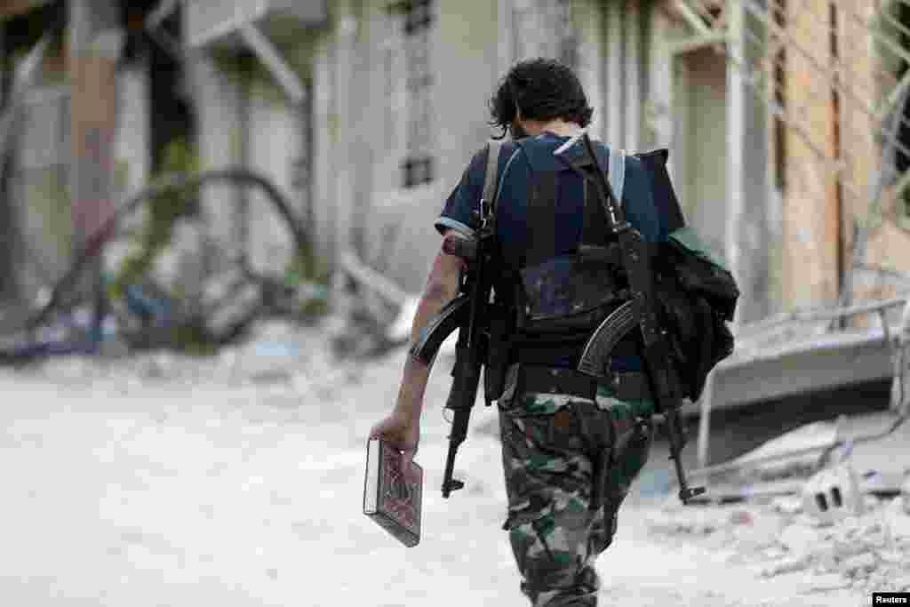 A Free Syrian Army fighter carries a copy of the Koran as he walks along a street in Jobar, a suburb of Damascus. (Reuters/Bassam Khabieh)