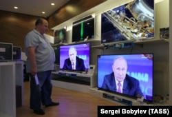 A man in an electronics shop in Moscow watches Russian President Vladimir Putin's televised question-and-answer session on June 15.