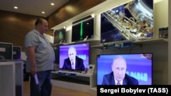 Покупатель в магазине бытовой техники в Москве, где на экранах телевизоров транслируют выступление президента России Владимира Путина