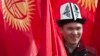 A man wearing the Kyrgyz national hat poses with national flags before a rally marking the Day of Flag and the Day of Kalpak in Bishkek in March 2013.