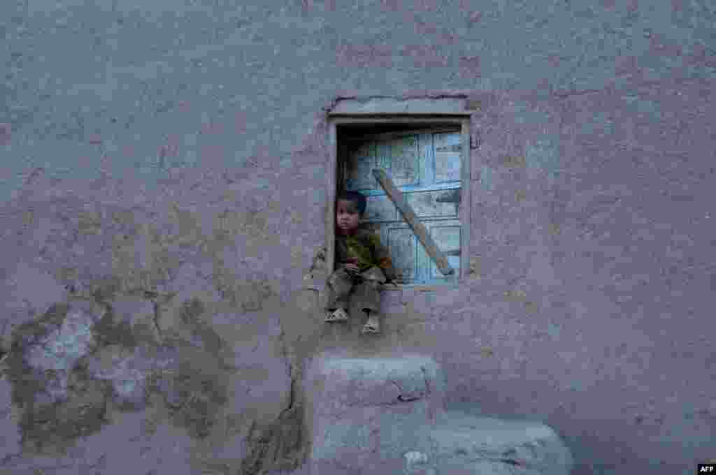 An Afghan child looks on as he sits in the doorway of a house on the outskirts of Jalalabad in Nangarhar Province on May 25. (AFP/​Noorullah Shirzada)