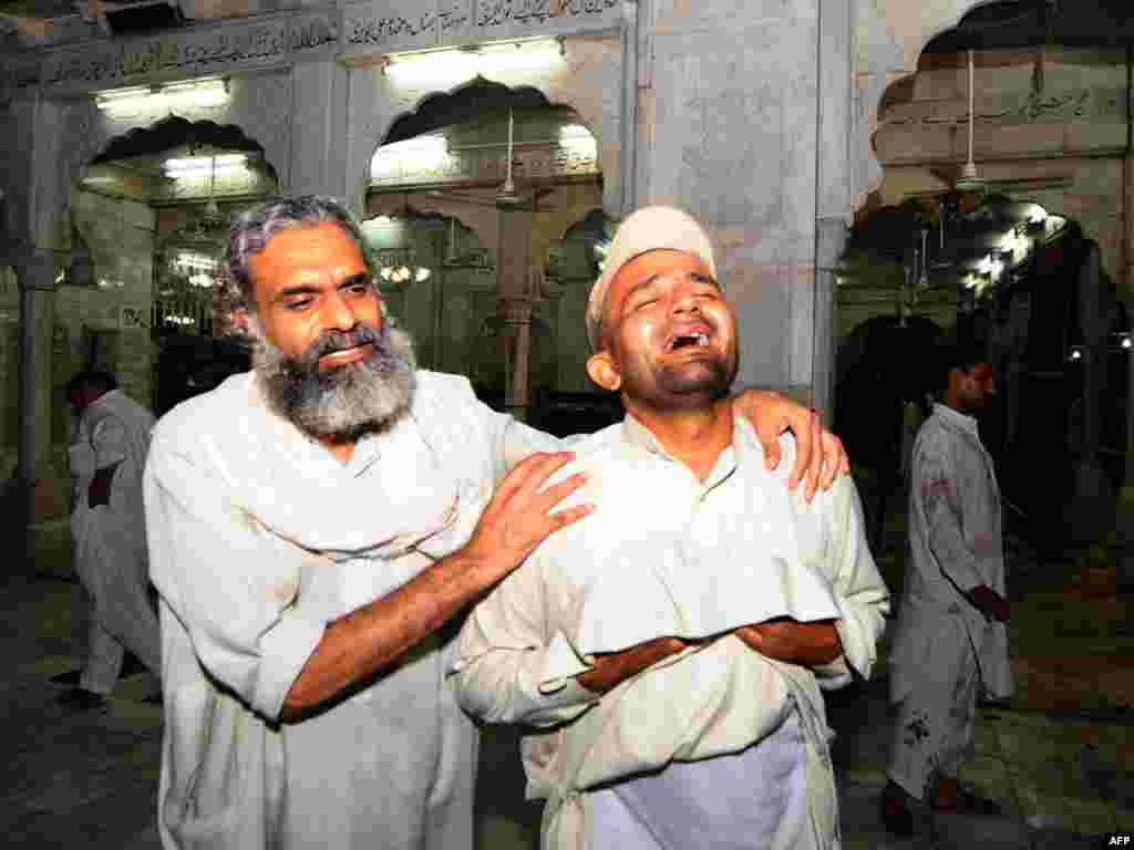 A Pakistani devotee comforts a man at the site of a double suicide bombing at a Sufi shrine in Lahore on July 2. At least 40 people were killed and more than 120 wounded at the shrine, the tomb of Sufi saint Data Gunj Bakhsh. Photo by Arif Ali for AFP