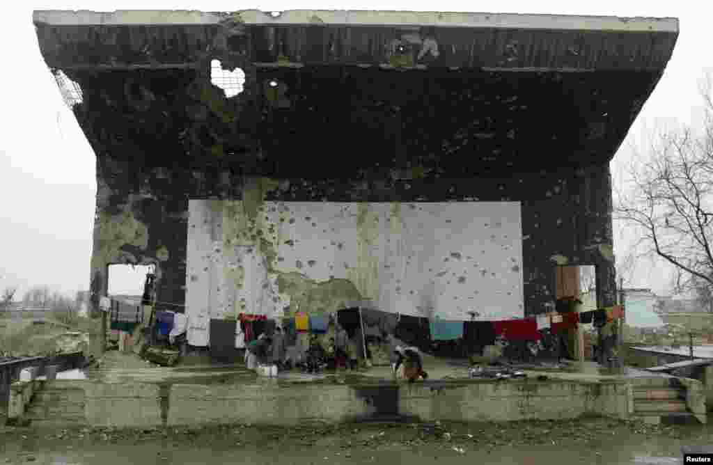 Afghan refugees live on the destroyed stage of the outdoor theatre atthe former Russian cultural center in Kabul December 13, 2002.