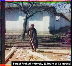 Көше бойында жаңа кесілген ағаштың қабығын аршып жатқан ағаш шебері.