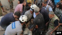 Syrian civil-defense volunteers, known as the White Helmets, hold the body of a young man after he was pulled from the rubble following a government air strike on the rebel-held neighborhood of Karm Homad in the northern city of Aleppo on October 4.