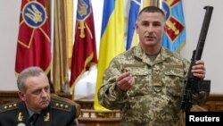 A Ukrainian military commander (right) shows a rifle seized from Russian soldiers as Colonel General Viktor Muzhenko, chief of the General Staff and commander-in-chief of the armed forces of Ukraine, looks on during a news conference in Kyiv on May 18.