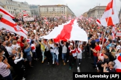 დემონსტრანტები ბელარუსის უზარმაზარი ისტორიული დროშით. მინსკი, 2020 წ. 23 აგვისტო.