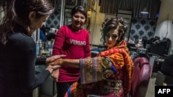 An Afghan bride dressed in a traditional wedding gown is attended by a beautician ahead of her wedding party in Kabul in 2017.