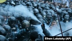Prvi sukobi dogodili su se ispred ukrajinske vlade u Kijevu 24. novembra. Na ovoj slici, demonstranti i pripadnici interventne policije raspršuju suzavac jedni u druge.