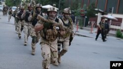 Afghan and international special forces run to the site of a clash between Afghan security forces and Taliban fighters in Kabul on May 24. 