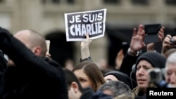 Человек держит табличку Je Suis Charlie во время церемонии на площади Республики в память о жертвах стрельбы во французской сатирической газете Charlie Hebdo в Париже, Франция, 10 января 2016 года