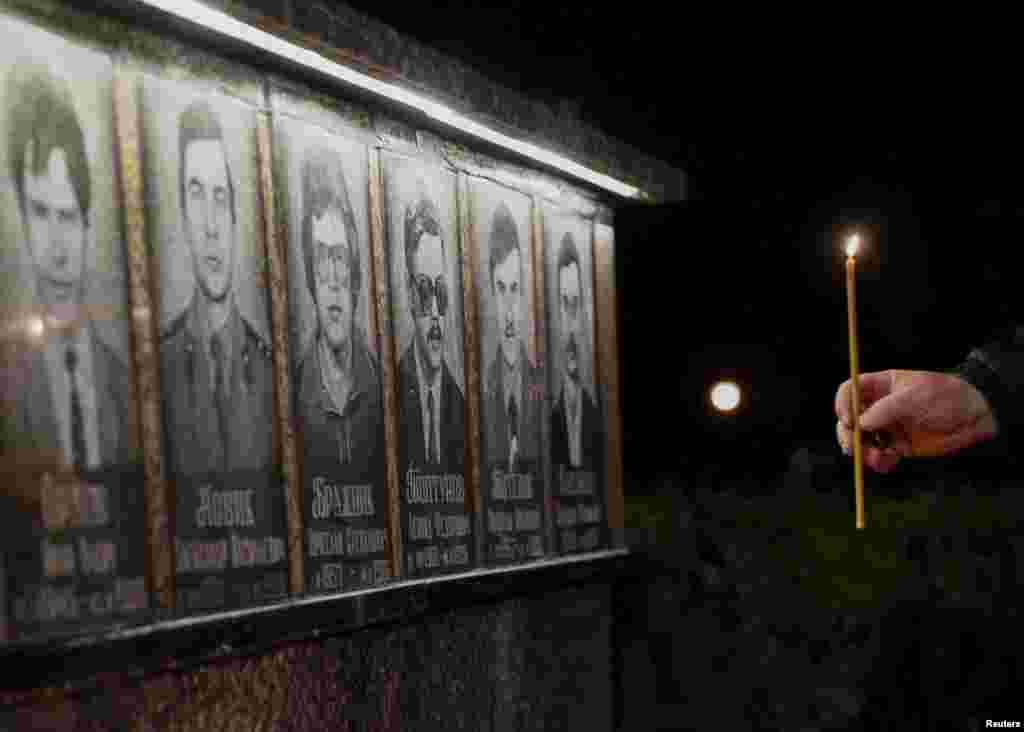 Чоловік запалює свічку біля меморіалу, присвяченого пожежникам та працівникам, які померли після катастрофи на Чорнобильській АЕС. Місто Славутич, 26 квітня 2016 року