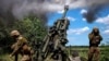 Mai mulți militari ucraineni, în timp ce folosesc un sistem de artilerie Howitzer M777 în apropierea frontului din estul Ucrainei, 6 iunie 2022. 