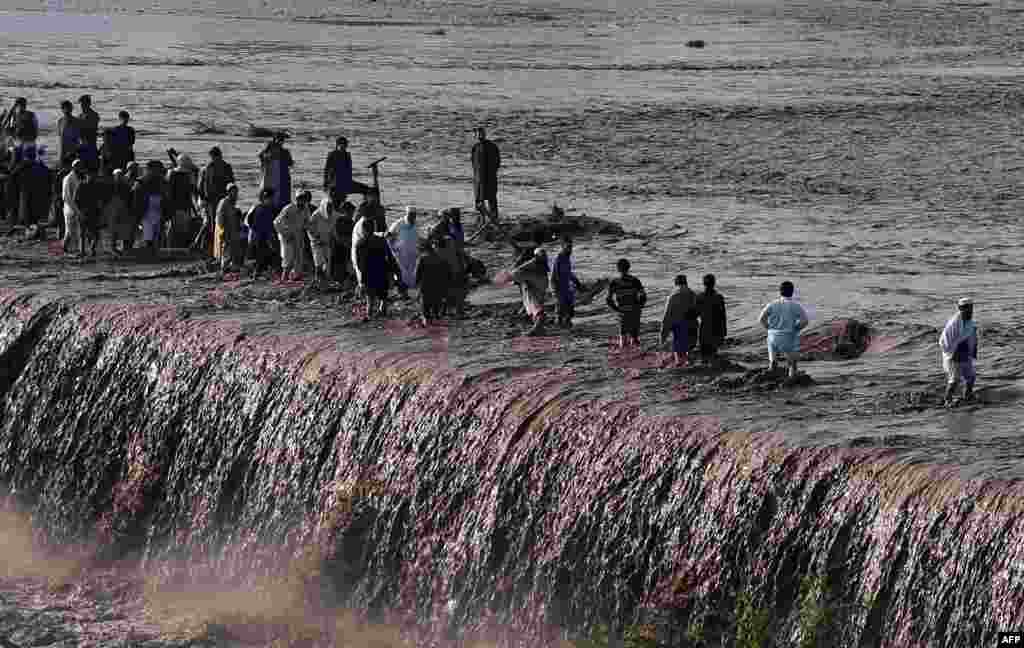 Residents cross a flooded street following heavy rain on the outskirts of Peshawar, Pakistan, on April 4. (AFP/A. Majeed)