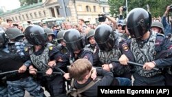 Russian police officers push a teenager during a rally protesting retirement-age hikes in St. Petersburg on September 9.