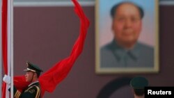 China -- A paramilitary police officer collects the Chinese national flag during a flag-lowering ceremony in front of a giant portrait of the late chairman Mao Zedong on Beijing's Tiananmen Square in Beijing, 04Mar2013