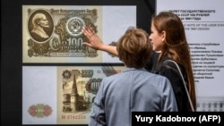 Жените разглеждат уголемени банкноти от рубли от съветската ера, показани на изложба на открито в центъра на Москва. Снимката е илюстративна.