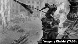 Eyni yerdən çəkilmiş başqa bir şəkildə sovet əsgərinin həm sağ, həm də sol qolunda saat olduğu görünür. Bu da Sovet Ordusunda olan talançılığın sübutudur. Khaldei danışırmış ki,TASS-dakı müdiri onu yanına çağıraraq diqqətini bu detala yönəldib: “Gerçək sovet əsgəri talançılıq etməz, tez bunu düzəlt və neqativdən götür”. 28 yaşlı fotoqraf lentdən sancaqla ikinci qol saatını qaşıyıb-silib.