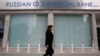 A woman walks past a closed branch of the Russian Commercial Bank in Nicosia, Cyprus. Natalya Orlova says Cyprus's liquidity crisis will become clear when the banks reopen.