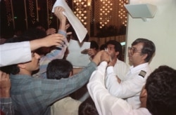A duty manager for Iran Air hands out a list of those people who were on board Iran Air Flight 655 to grieving friends and relatives in Dubai on July 4, 1988.