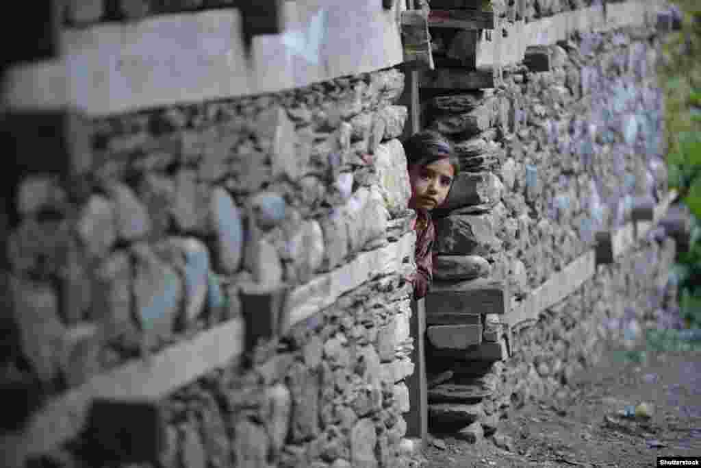 A little Kalash girl peers out of her house. In 2013, the Pakistani Taliban vowed the Kalash would be “eliminated, along with their protectors, the Western agents, if they do not embrace Islam." (Photo by Shutterstock).