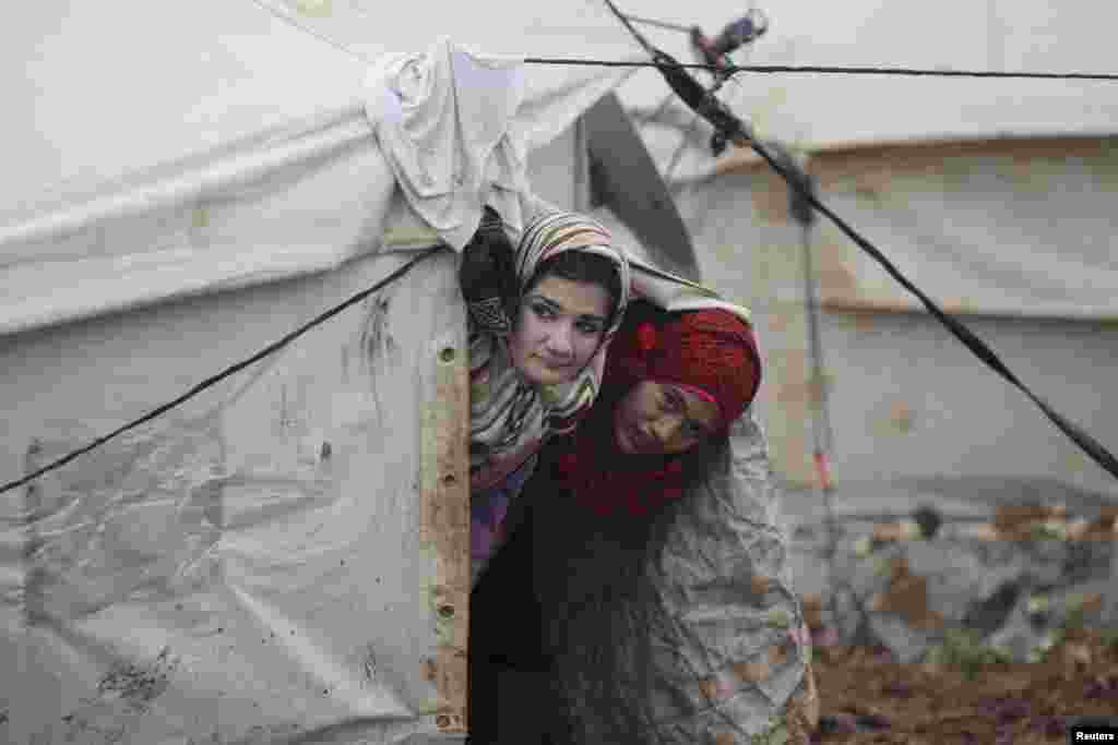 Internally displaced girls look out from their tent inside the Al-Karameh refugee camp beside the Syrian-Turkish border in Syria's northern Idlib countryside. (Reuters/Khalil Ashawi)