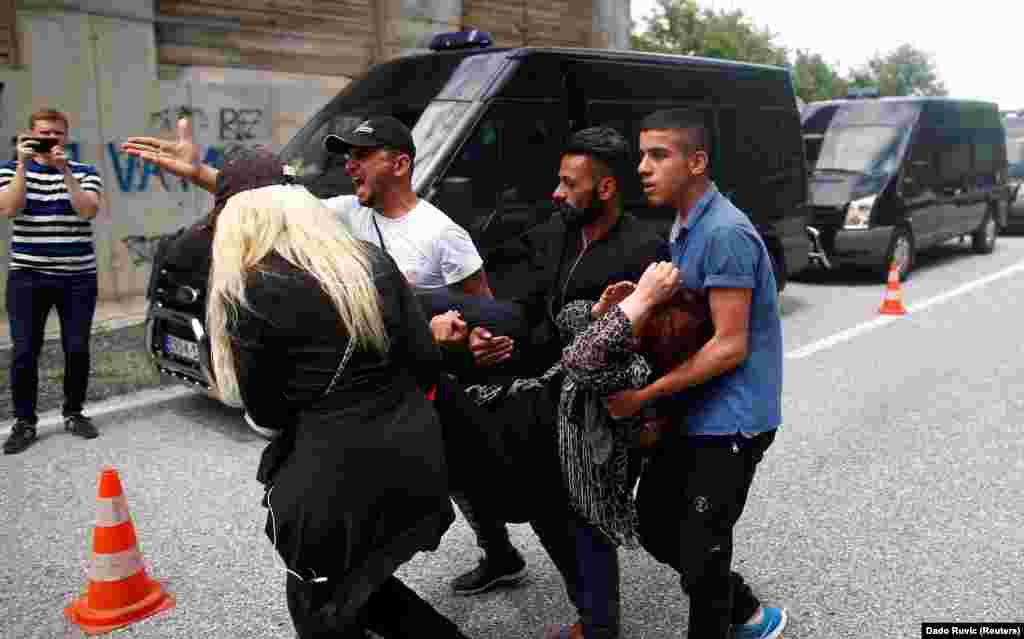 People help a migrant woman who fell ill after her bus to an asylum center was stopped in Bosnia and turned back by police on May 18. (Reuters/Dado Ruvic)