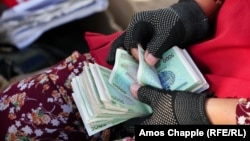 A woman counts money at a market in Bukhara. 