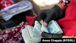 Uzbekistan -- A woman counting money in a market in Bukhara. August 4, 2018