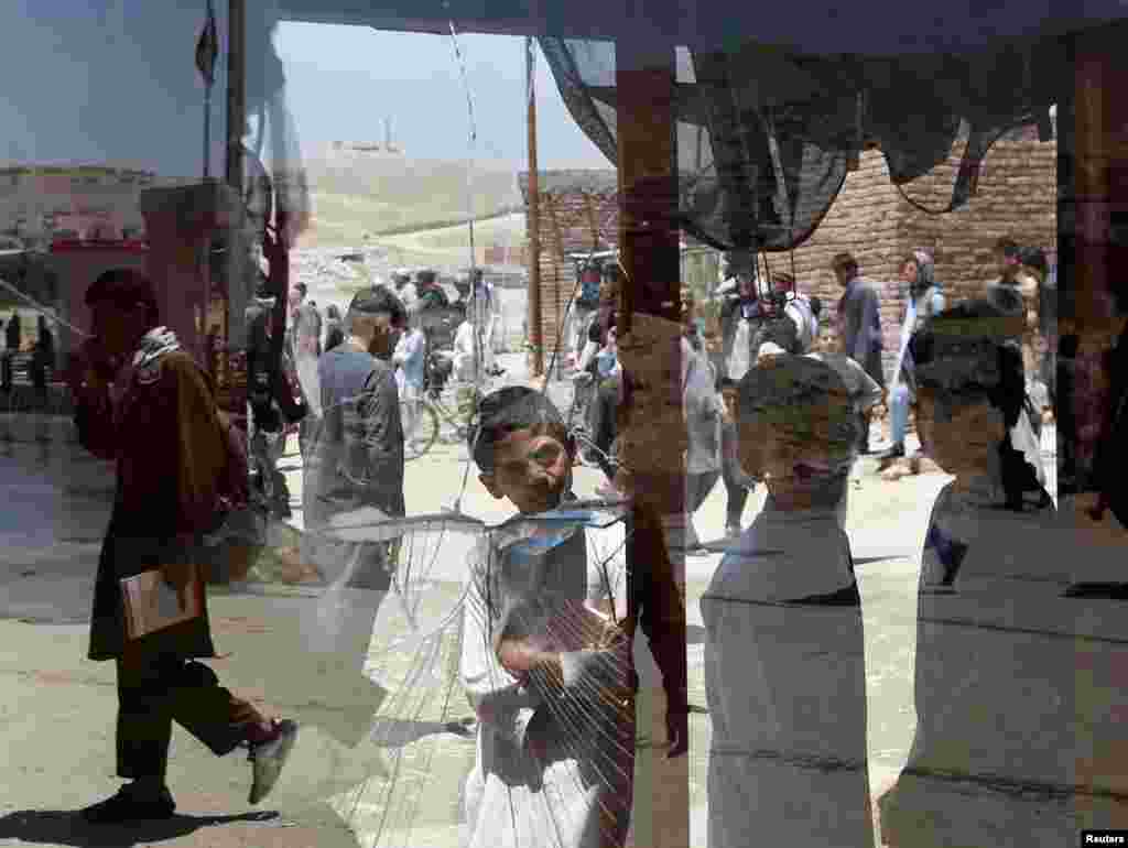 Afghan boys look at the damaged window of a shop after a deadly suicide attack in the west of Kabul on May 25. (Reuters/Mohammad Ismail)