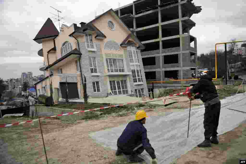 Workers cordon off a leaning building in the Russian Black Sea resort of Sochi. A three-story apartment building under construction began to lean after a vehicular road traffic tunnel being constructed for the 2014 Winter Olympics collapsed nearby. (AFP/Mikhail Mordasov)