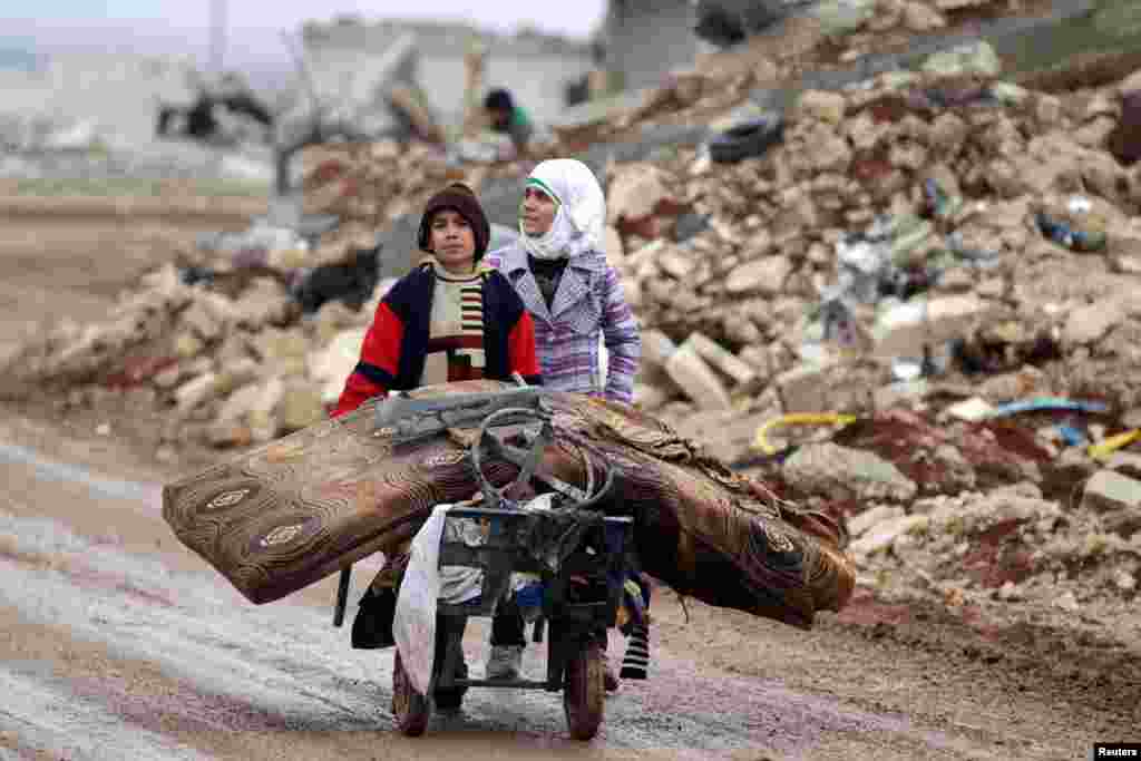 Samah, 11, and her brother Ibrahim transport salvaged belongings from their damaged house in the village of Doudyan in northern Aleppo Governorate, Syria. (Reuters/Khalil Ashawi)