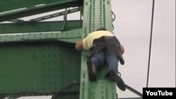 A Serbian news report shows a man sleeping precariously on a bridge over the Sava River in Belgrade. 