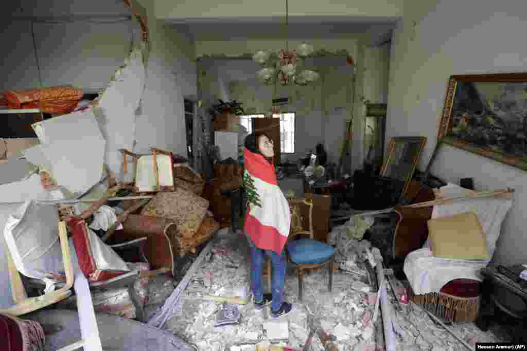 Farah Mahmoud, wrapped in Lebanese national flag, checks her parents destroyed apartment after Tuesday's explosion in the seaport of Beirut, Lebanon, Thursday, Aug. 6, 2020.