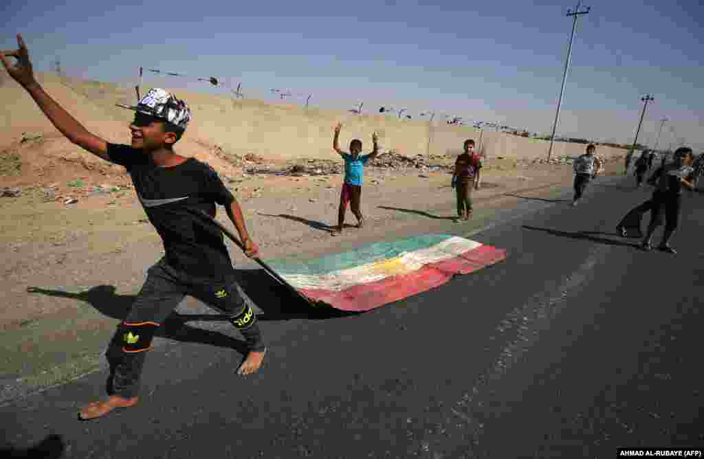 An Iraqi boy drags a Kurdish flag as Iraqi forces advance towards the center of Kirkuk during an operation against Kurdish fighters on October 16. (AFP/Ahmad al-Rubaye)