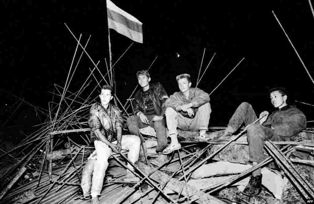 Young people sit on a barricade in front of the Russian White House in central Moscow early on August 20, 1991.