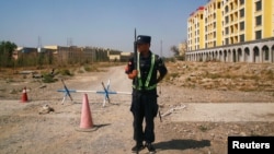 Un polițist chinez păzește intrarea către unul din așa-zisele ,,centre de re-educare" din Xinjiang.