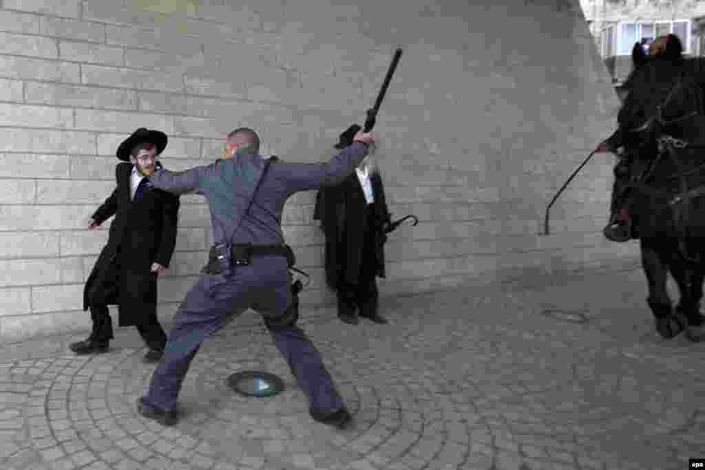 A police officer brandishes his baton at an ultra-Orthodox young man during the February 6 protests in Jerusalem. (EPA/Jim Hollander)