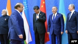 Pakistani Prime Minister Nawaz Sharif (second from left) walks past (left to right) Indian Prime Minister Narendra Modi, Chinese President Xi Jinping, Kazakh President Nursultan Nazarbaev, and Russian President Vladimir Putin as he arrives for group photo at the Shanghai Cooperation Council summit in Astana on June 9.