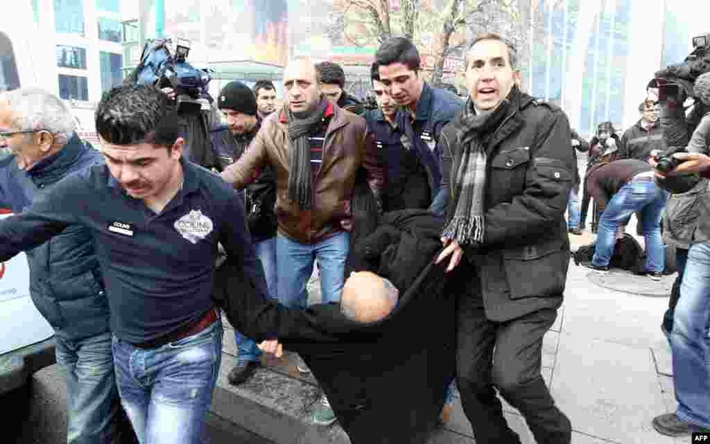 Polislə qarşıdurmada yaralanan aksiya iştirakçısını həmkarları qarşıdurma meydanından çıxarırlar. Ankara, 12 mart 2014