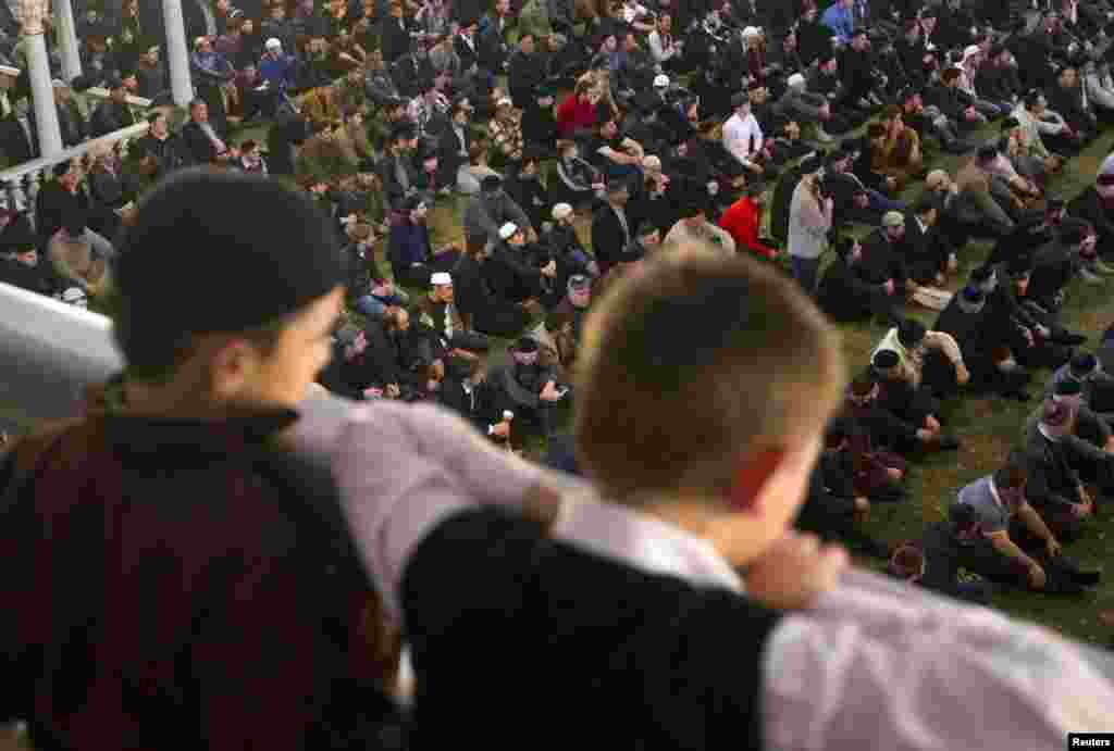 Boys watch as men prepare to pray at a mosque in Grozny.