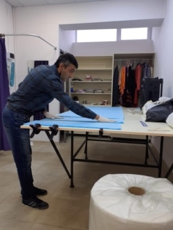 An Echmiadzin man who loaned space in his factory to the team of volunteers prepares to cut the medical fabric used in the masks.